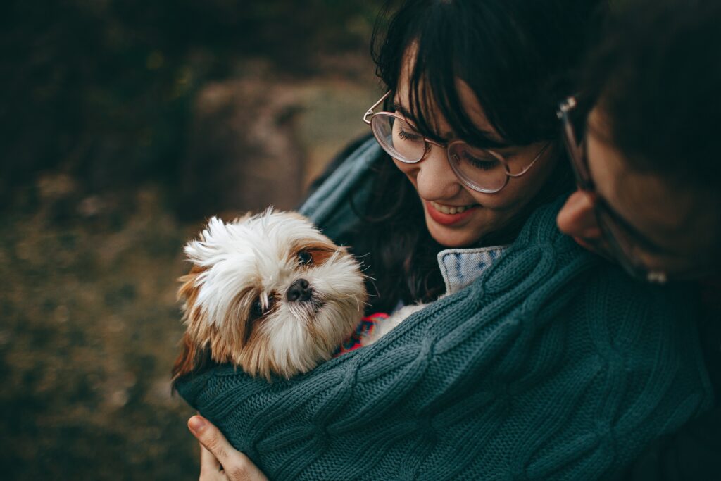 A small fluffy puppy wrapped in a jumper with a couple looking smitten